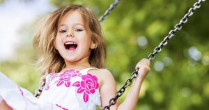 Sweet smiling girl playing on a swing