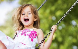 Sweet smiling girl playing on a swing
